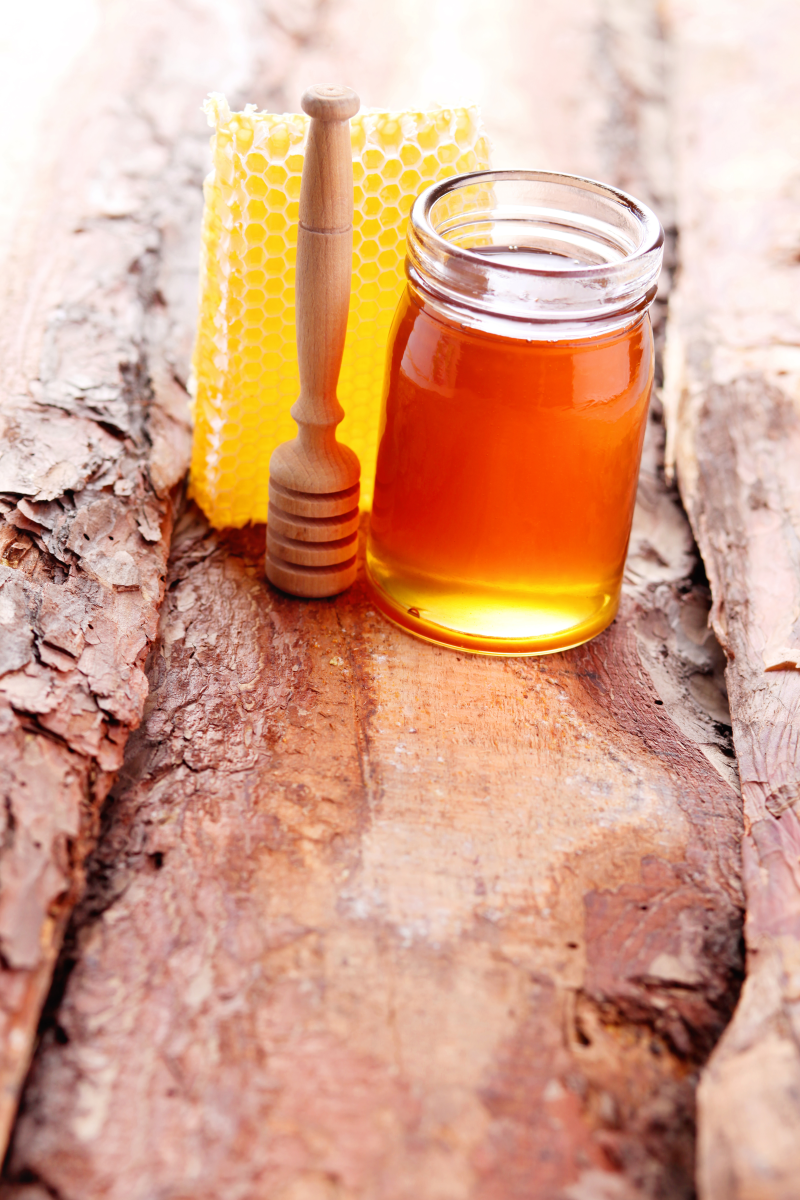 木板上的蜂蜜与搅拌棒摄影高清图片